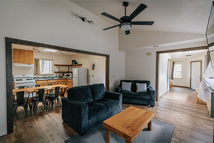 Photo of a kitchen. There is a table with six chairs, a refrigerator, a counter, and a tile floor.